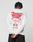 A person with short, twisted hair stands facing away, wearing an oversized white LIVE FAST DIE YOUNG LFDY We Walked Longsleeve featuring red flame graphics and “I WALKED SO THEY CAN RUN” on the back.