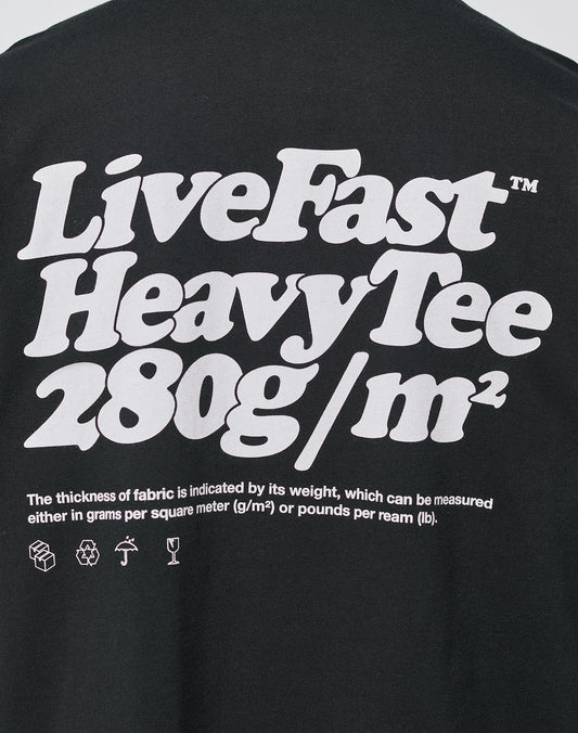 The LIVE FAST DIE YOUNG Basic 280 Tee is a black oversize fit cotton t-shirt with a bold white front print, fabric thickness info in small text, and washing, recycling, and handling icons at the bottom.