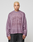 A person with short, bleached blond hair faces the camera wearing the LFDY Flash Jersey by LIVE FAST DIE YOUNG—an oversized purple mesh long-sleeve with a bold front print—paired with black jeans against a light gray background.