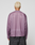 A person with short, bleached blond hair is seen from behind wearing the LIVE FAST DIE YOUNG LFDY Flash Jersey, an oversize long-sleeved sheer purple mesh top, and dark gray denim pants against a plain light background.