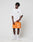 A person with short, twisted hair and a relaxed posture wears a loose white t-shirt, LIVE FAST DIE YOUNG LFDY Praying Mesh Shorts in bright orange with white graphics and an elastic waistband, plus white socks and sneakers against a plain white background.