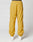 Model wearing LIVE FAST DIE YOUNG LFDY Trackpants in mustard yellow with elastic waistband and cuffs, paired with white sneakers. Photo shows the loose polyester fit from the back against a plain white background.