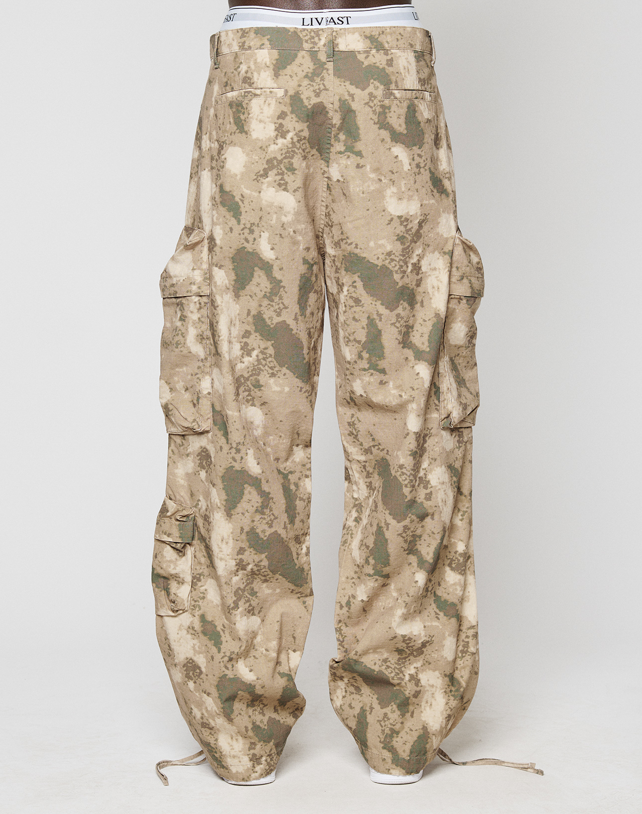 The LFDY Cargo by LIVE FAST DIE YOUNG features a tan and green camouflage print, Cargo Taschen, large side pockets, wide fit, drawstring hems, a visible branded waistband, and is crafted from 100% Baumwolle.