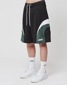 A person stands against a white background wearing LIVE FAST DIE YOUNG Basic Trackshorts with curved white and dark green accents, an elastischer Bund, LFDY logo-print white socks, and white Nike sneakers.