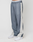 A person wears blue-gray LFDY DY Trackpants by LIVE FAST DIE YOUNG with a wide fit, elastic waistband reading "LIVE FAST," white side stripes, and white sneakers, standing against a plain light background.