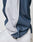 Close-up of a person wearing LIVE FAST DIE YOUNG LFDY DY Trackpants made of soft polyester with an Elastikbund. The blue pants have a white stripe and bunch slightly at the ankle, covering part of white sneakers.