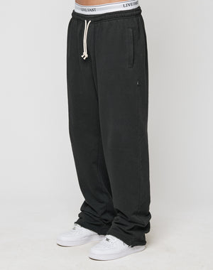 A person in LIVE FAST DIE YOUNG LFDY Lightweight Joggers with elastic waistband and drawstring, paired with white sneakers and a visible white LIVE FAST waistband, stands against a simple light background.
