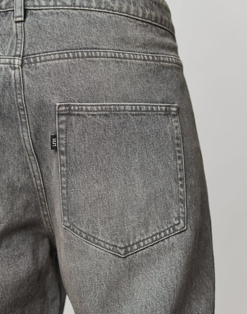 Close-up of the back pocket on the Rhomb Wide Denim by LIVE FAST DIE YOUNG. Crafted from 100% cotton, it features a baggy fit, wide straight leg, visible stitching, a black tag, and detailed denim texture.