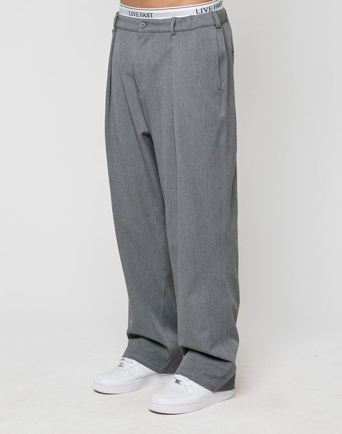 Someone wears LIVE FAST DIE YOUNG Wide Casual Pants in gray with an elastic waistband, styled with white sneakers. The LIVE FAST underwear waistband is visible above the straight-leg pants against a plain white background.