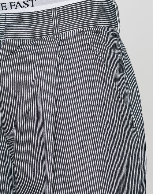 Close-up of LIVE FAST DIE YOUNG LFDY Twill Shorts in black and white vertical stripes, featuring a waistband with belt loops and a wide straight leg. Part of a tucked-in white shirt with partial text is also visible.