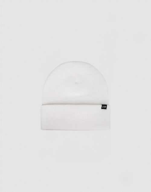 The Basic Beanie by LIVE FAST DIE YOUNG is a plain white polyacryl knit with a folded cuff and a small black front tag. Light grey background. Handwäsche recommended for lasting quality.