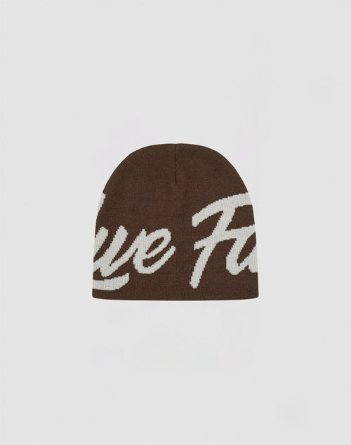 The LFDY Jacquard Beanie by LIVE FAST DIE YOUNG is a brown Polyacryl knit hat with large white cursive logo lettering on the front, shown against a plain light background.