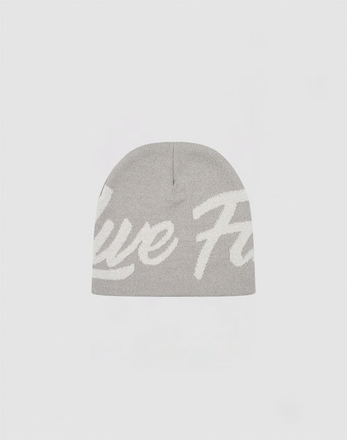 The LFDY Jacquard Beanie by LIVE FAST DIE YOUNG is a light gray knit beanie made from 100% Polyacryl, with large white cursive text partially visible across the front, shown against a plain white background.
