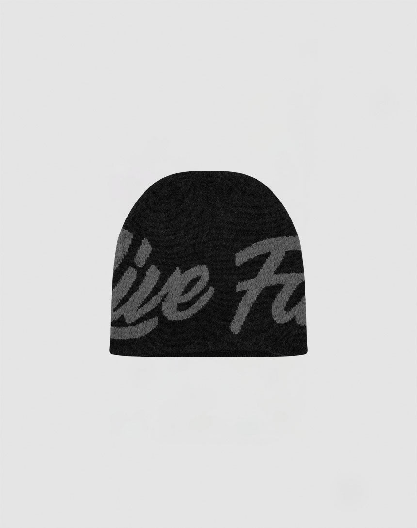 The LFDY Jacquard Beanie by LIVE FAST DIE YOUNG features black polyacryl fabric with a large, subtle gray script design on the front, shown against a light gray background.