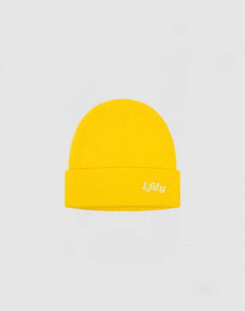 The LFDY Beanie by LIVE FAST DIE YOUNG is bright yellow, made from polyacryl, with a folded brim and white embroidered Lfdy Logo-Stick on the front, shown against a light gray background.