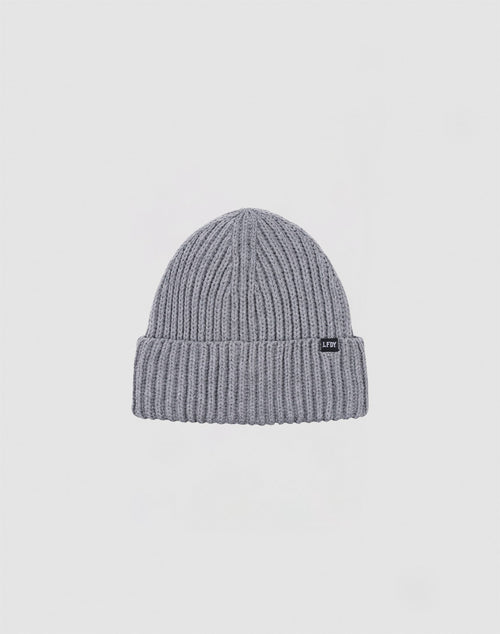 The LIVE FAST DIE YOUNG Rib Knit Beanie in grey is crafted from soft polyacryl, featuring a folded brim and a small black rectangular front tag, shown against a plain white background.