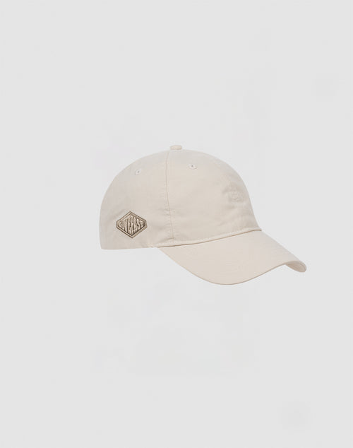 The Basic Cap by LIVE FAST DIE YOUNG is beige, made from Baumwolle and Polyester, with a curved brim, small diamond-shaped patch on the front left, and an adjustable Klettverschluss. Shown on a plain white background.