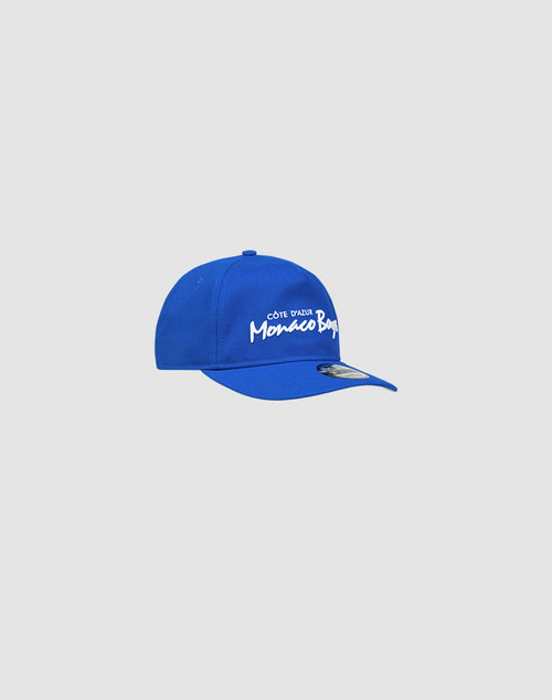 A bright blue LIVE FAST DIE YOUNG X NEW ERA Monaco Boys 9Fifty A-Frame cap with white “Côte d’Azur Monaco Boys” embroidery on the front, shown against a plain light gray background.