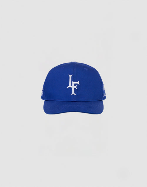 The LF 10th Snapback by LIVE FAST DIE YOUNG is a blue 100% cotton baseball cap with a white LF Multi-Logo embroidered on the front, shown on a light gray background. Features an adjustable snap closure.