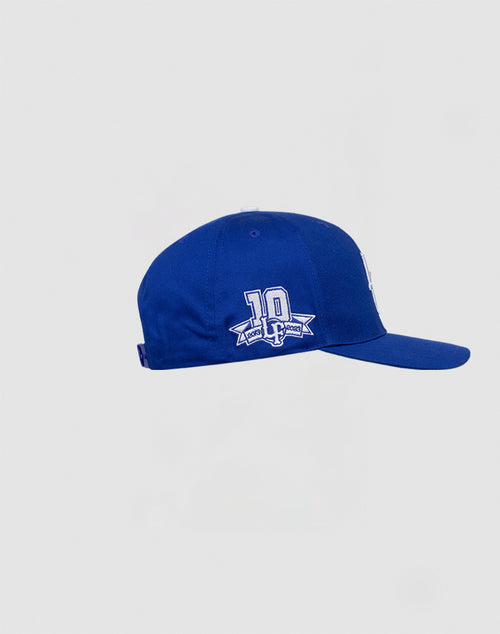 The LF 10th Snapback by LIVE FAST DIE YOUNG is a royal blue 100% Baumwolle cap with a flat brim, a 10 year anniversary patch, and a white embroidered side logo, shown on a plain light gray background.