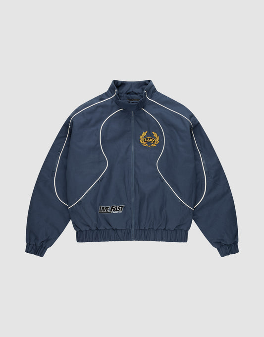 The LFDY Canvas Jacket by LIVE FAST DIE YOUNG is navy blue with white piping, multicolor embroidered logos including a yellow crest on the left chest, a LIVE FAST patch at the waistband, plus elastic cuffs and hem in a regular fit. | plain