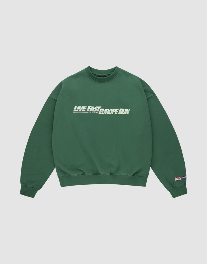 The LFDY Europe Run Sweater by LIVE FAST DIE YOUNG is a forest green oversized crewneck with “LIVE FAST, RACE RUN” in bold white and green front print and small flag patches on the left sleeve near the cuff. Made from soft Baumwolle. | plain