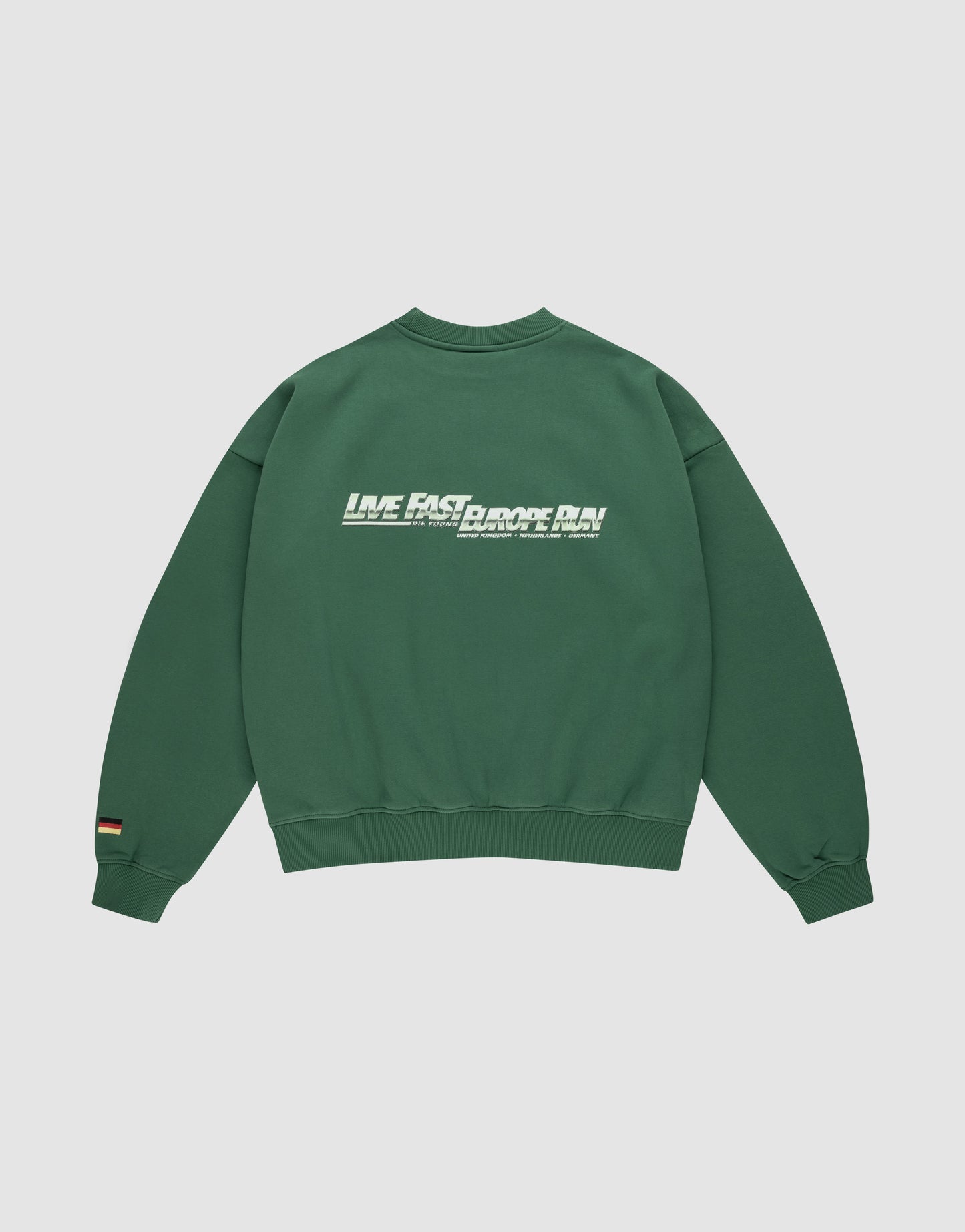 The LFDY Europe Run Sweater by LIVE FAST DIE YOUNG is a forest green oversized cotton sweatshirt with ribbed cuffs and hem, white "LIVE FAST, CHOOSE SLOW." text on the back, and a small Flaggen-Stick tag on the left sleeve.