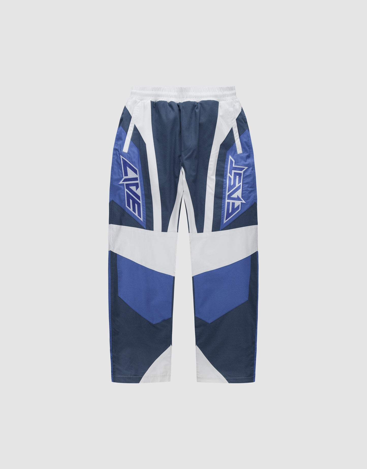 LFDY Cross Pants by LIVE FAST DIE YOUNG in blue, white, and navy feature an elastic waistband, geometric patterns, Stick Applikationen details, and "LIVE" and "FAST" printed on each thigh. Displayed flat on a plain light background.
