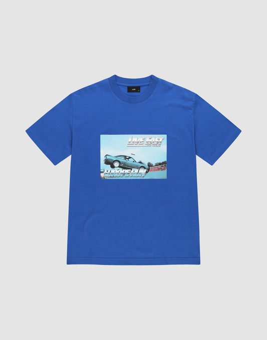 The LFDY Crash Kid Tee by LIVE FAST DIE YOUNG is a blue, regular fit shirt in 100% cotton, with a car mid-jump frontprint and bold white "LIVE FAST" above and "DRIVE SLOW" below. | plain