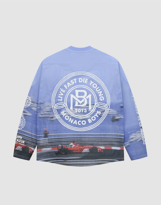 The LFDY Yacht Jersey by LIVE FAST DIE YOUNG is a blue oversize long-sleeve shirt with racing car and track graphics on the back, a large white circular logo, and additional white graphics on the sleeves and lower back. | plain