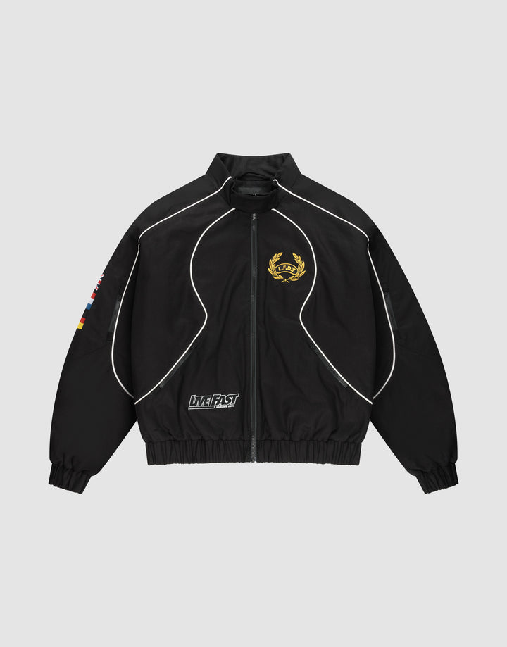 The LFDY Canvas Jacket by LIVE FAST DIE YOUNG is a black regular-fit zip-up with white piping, gold crest on the left chest, flag patches on the right sleeve, Multilogo Stickereien, and a "LIVE FAST" text patch near the left pocket. | plain