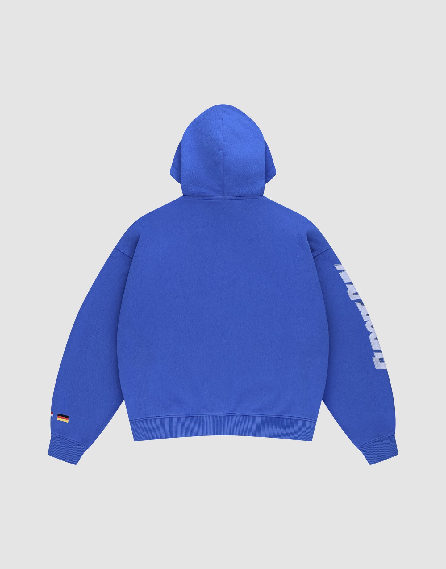 The LFDY Team Hooded Zip by LIVE FAST DIE YOUNG is an oversized bright blue hoodie, shown from the back, with white text on the right sleeve and a small tag with a black, red, and yellow flag near the left wrist.