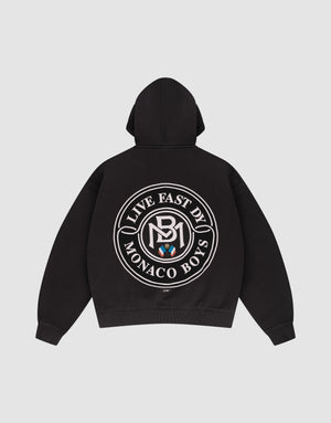 The LFDY Monaco Boys Hooded by LIVE FAST DIE YOUNG is a black oversized hoodie with a large circular white "Live Fast By Monaco Boys" logo and emblem on the back. Shown laid flat on a plain light gray background. | plain