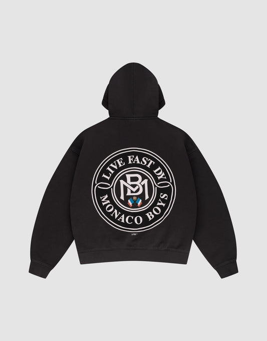 The LFDY Monaco Boys Hooded by LIVE FAST DIE YOUNG is a black oversized hoodie with a large circular white "Live Fast By Monaco Boys" logo and emblem on the back. Shown laid flat on a plain light gray background. | plain