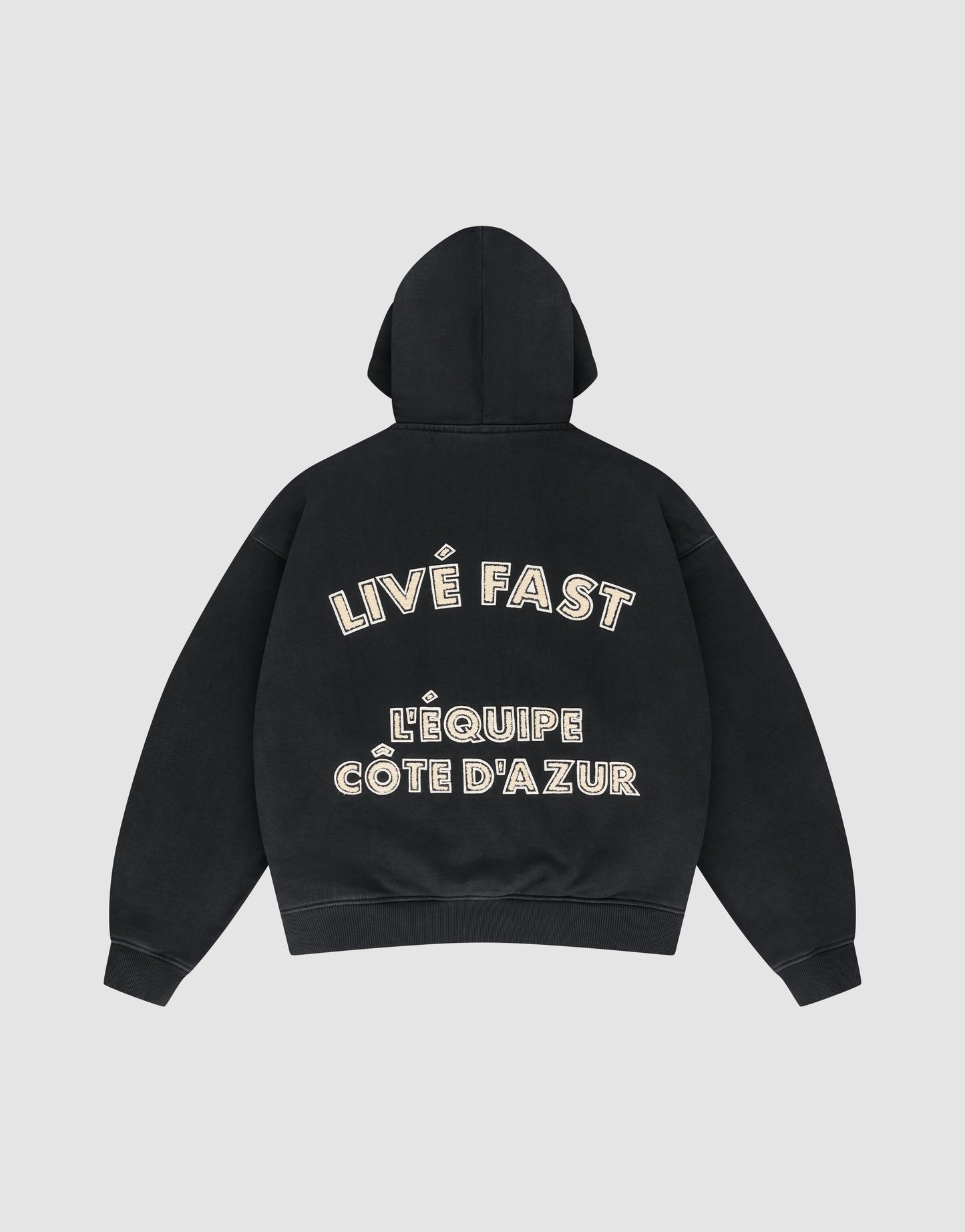 The LFDY L'Équipe Hooded Zip by LIVE FAST DIE YOUNG is a black oversize hoodie with LIVE FAST and LÉQUIPE CÔTE DAZUR in bold white lettering on the back, plus a soft waffle lining for extra comfort.
