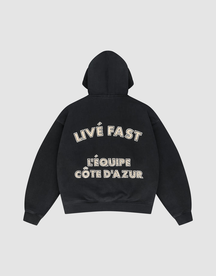 The LFDY L'Équipe Hooded Zip by LIVE FAST DIE YOUNG is a black oversize hoodie with LIVE FAST and LÉQUIPE CÔTE DAZUR in bold white lettering on the back, plus a soft waffle lining for extra comfort. | plain