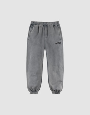 The LFDY Europe Run Jogger by LIVE FAST DIE YOUNG features gray, loose-fit sweatpants with an elastic waistband and cuffs, side pockets, and "LIVE FAST" printed in black on the left thigh, displayed on a plain light background. | plain