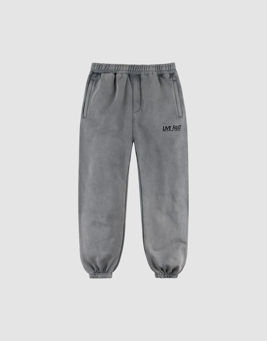 The LFDY Europe Run Jogger by LIVE FAST DIE YOUNG features gray, loose-fit sweatpants with an elastic waistband and cuffs, side pockets, and "LIVE FAST" printed in black on the left thigh, displayed on a plain light background. | plain