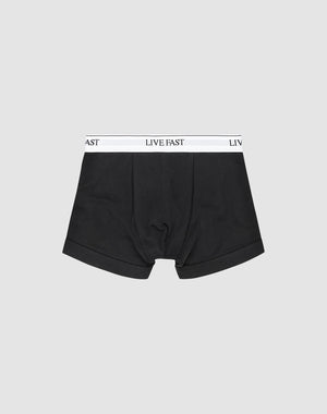 LIVE FAST DIE YOUNG Live Fast Trunks (2 Pack): Black mens boxer briefs made from cotton, with a white elastic waistband featuring LIVE FAST in black text, shown on a plain light gray background.