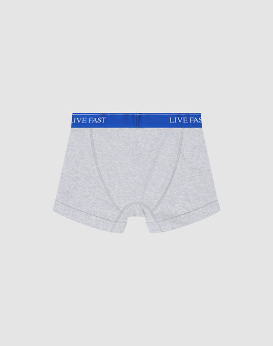 A pair of light gray Live Fast Trunks by LIVE FAST DIE YOUNG in Regular Fit, made of soft cotton with a blue elastic waistband reading LIVE FAST in white, shown on a plain white background.