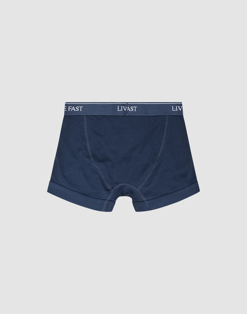 The LIVE FAST DIE YOUNG Live Fast Trunks (2 Pack) are navy blue men’s boxer briefs in a regular fit, made from soft cotton with an elastic waistband featuring white “LIVE FAST LIVAST” text on a dark band.