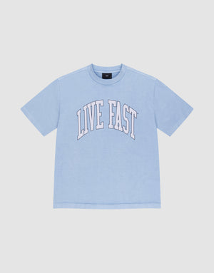 The LIVE FAST DIE YOUNG Live Fast College Tee is a light blue, 100% Baumwolle oversize short-sleeve shirt with "LIVE FAST" in large white arched letters on the front, shown on a plain white background. | plain