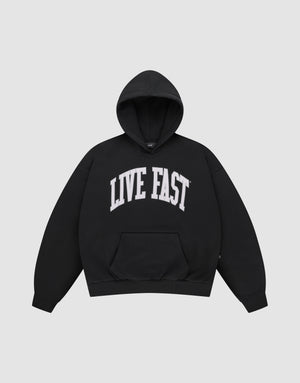 The LIVE FAST DIE YOUNG "Live Fast College Hooded" is a black, oversized cotton pullover featuring a front pocket and bold white “LIVE FAST” print across the chest. | plain