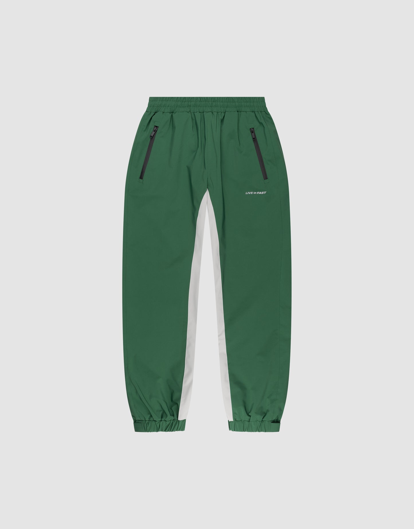 Basic Shell Pants by LIVE FAST DIE YOUNG feature an oversize fit, elastic waistband, black zippered pockets, white side panels, elastic cuffs, and reflective print—shown against a plain light grey background.