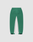 The LIVE FAST DIE YOUNG Basic Shell Pants feature a green color with white inner leg panels, elastic waistband, right back pocket, elastic cuffs, dark green adjustable ankle tabs, and an oversized fit. Displayed on a plain background.
