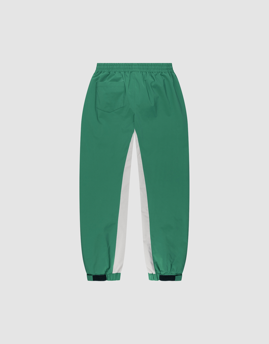 The LIVE FAST DIE YOUNG Basic Shell Pants feature a green color with white inner leg panels, elastic waistband, right back pocket, elastic cuffs, dark green adjustable ankle tabs, and an oversized fit. Displayed on a plain background.