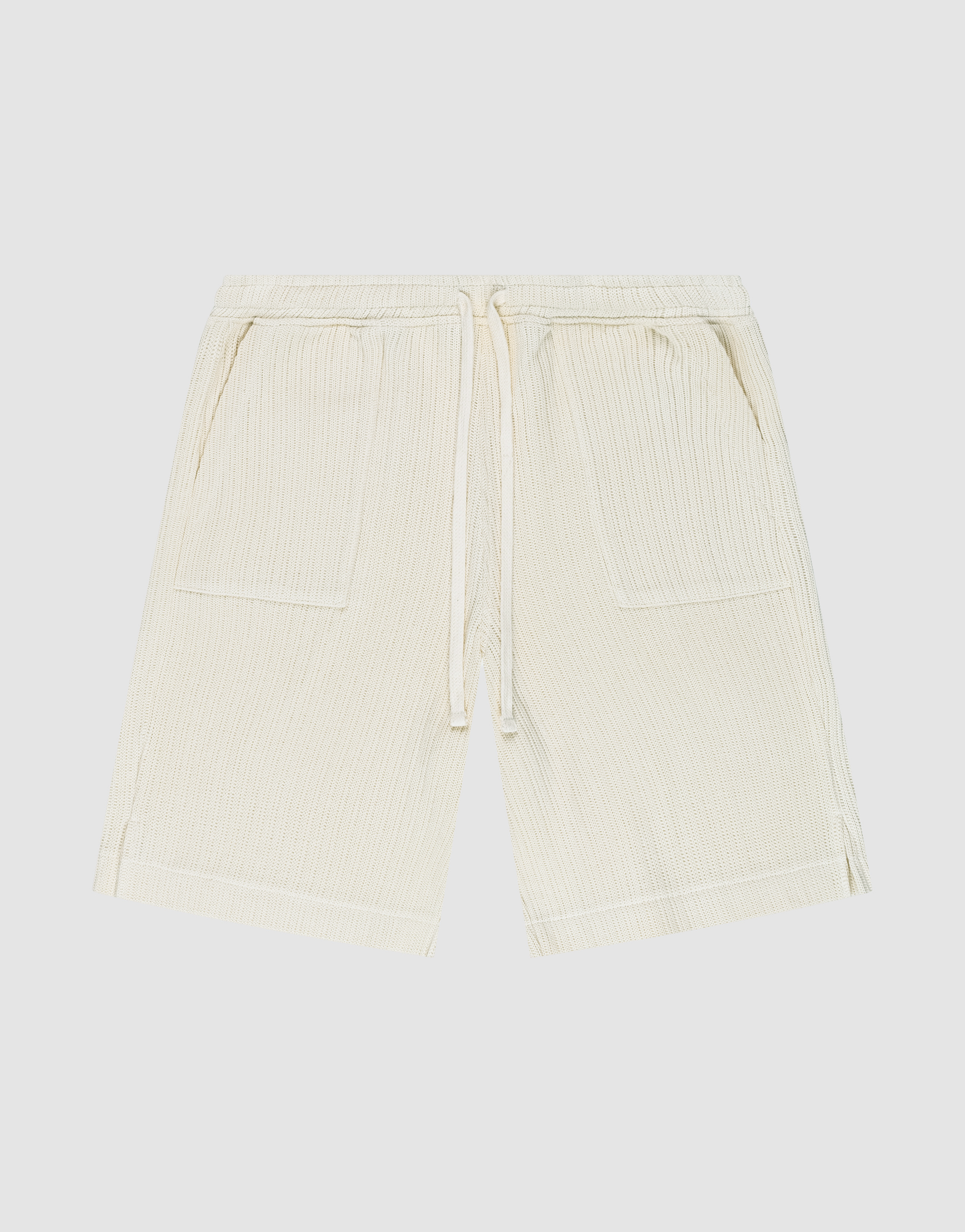 Die Basic Knit Shorts von LIVE FAST DIE YOUNG in Beige aus gerippter Baumwolle haben einen elastischen Bund mit Kordelzug, zwei aufgesetzte Taschen und sind knielang. Das Modell ist flach auf weißem Hintergrund ausgebreitet.
