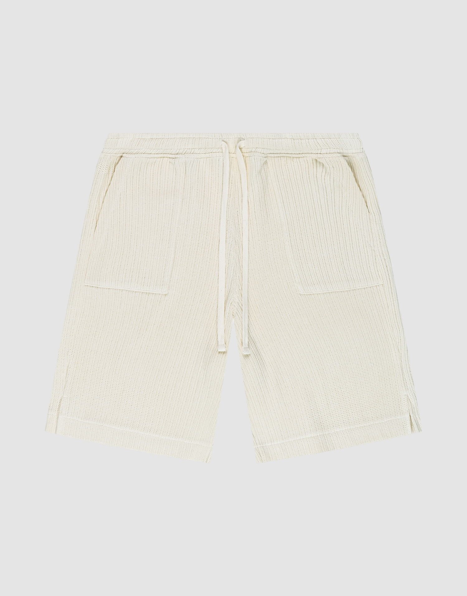 Die Basic Knit Shorts von LIVE FAST DIE YOUNG in Beige aus gerippter Baumwolle haben einen elastischen Bund mit Kordelzug, zwei aufgesetzte Taschen und sind knielang. Das Modell ist flach auf weißem Hintergrund ausgebreitet. | plain
