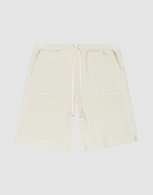 Die Basic Knit Shorts von LIVE FAST DIE YOUNG in Beige aus gerippter Baumwolle haben einen elastischen Bund mit Kordelzug, zwei aufgesetzte Taschen und sind knielang. Das Modell ist flach auf weißem Hintergrund ausgebreitet. | plain