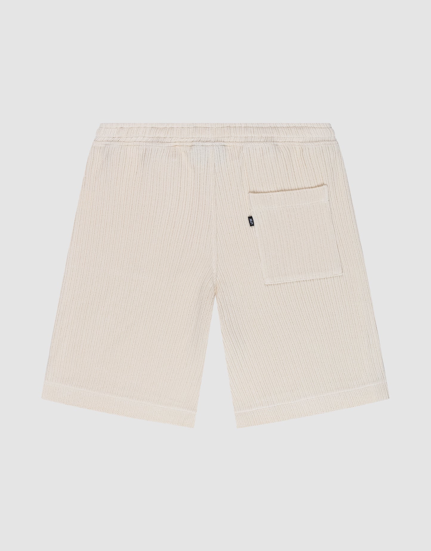 Back view of the LIVE FAST DIE YOUNG Basic Knit Shorts in beige with ribbed cotton fabric, elastic waistband, and a single large patch pocket on the right side, shown against a white background.